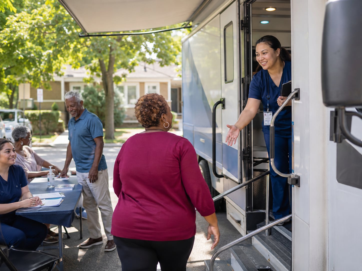 A nurse helps an older couple step into a mobile clinic van parked outdoors