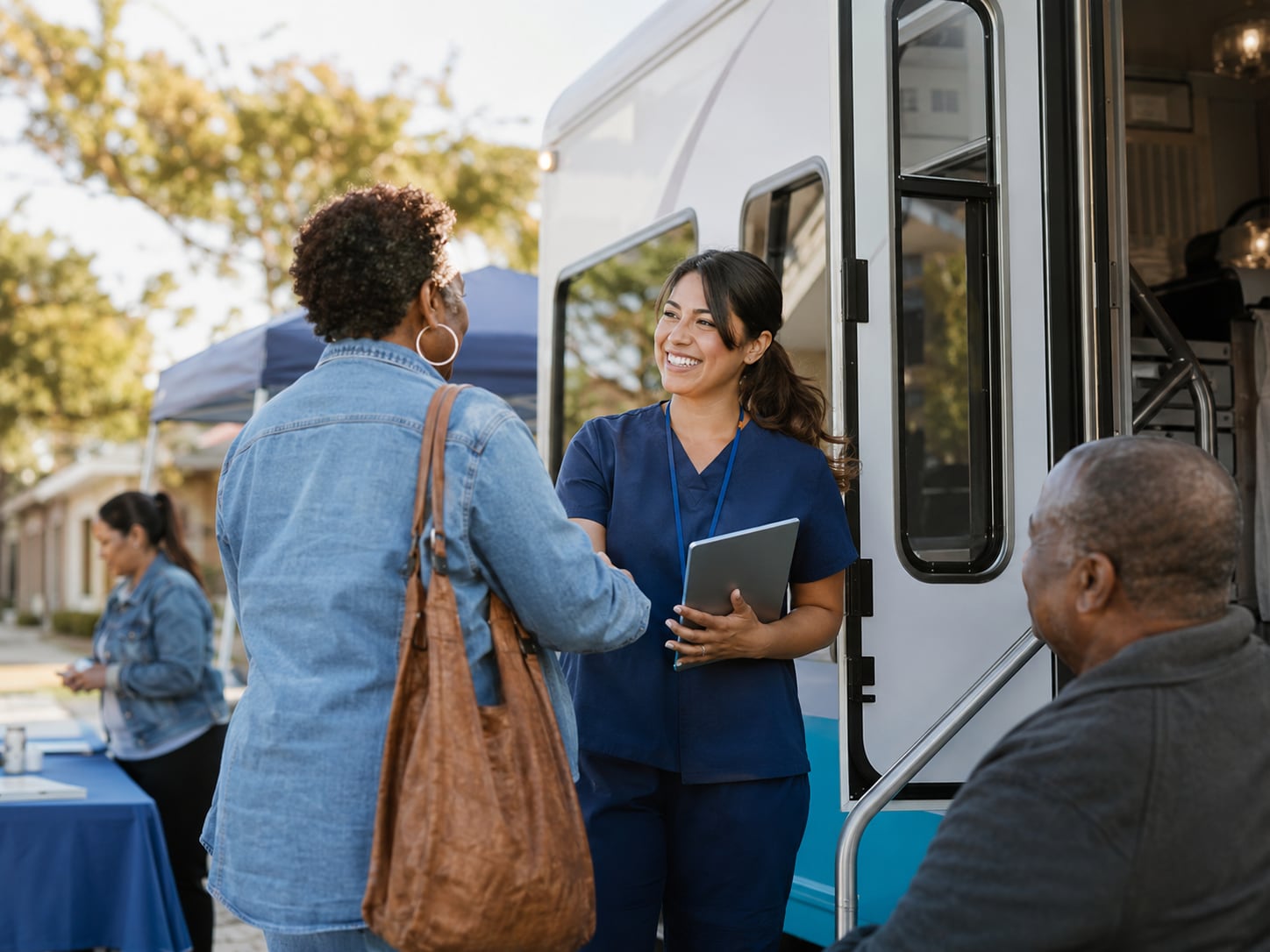 A nurse greets an older man at the door of a mobile clinic van