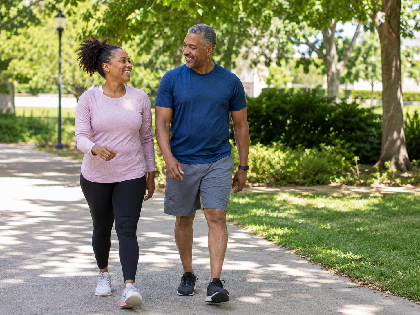 A woman and man in athletic wear walk together in a park