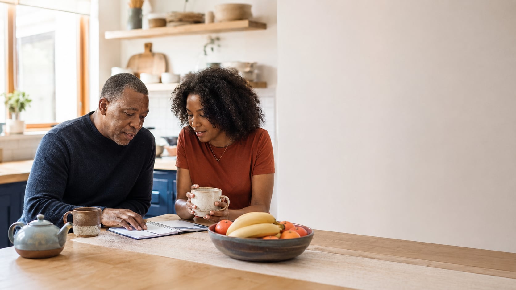 A couple at their kitchen table reading through notes together over coffee