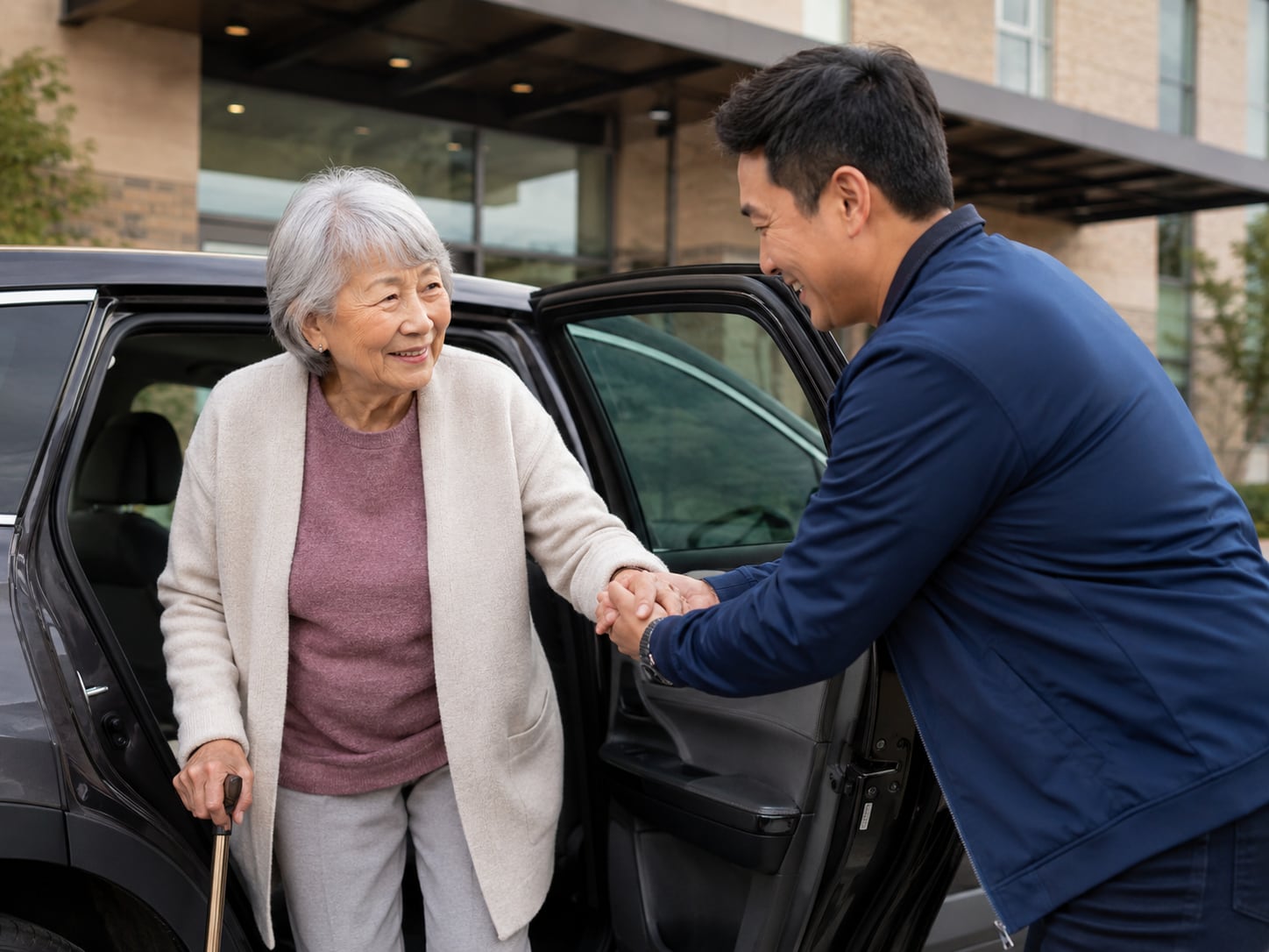 An older woman is helped out of a car and embraced by a man outside