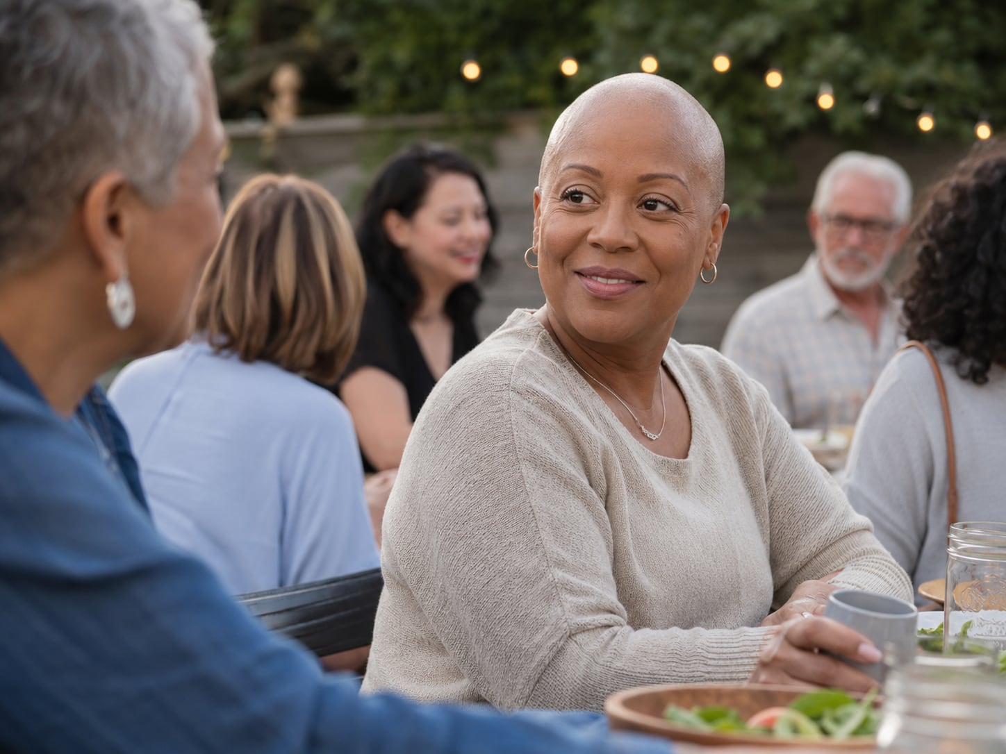 A group of older women sit outdoors talking and smiling together