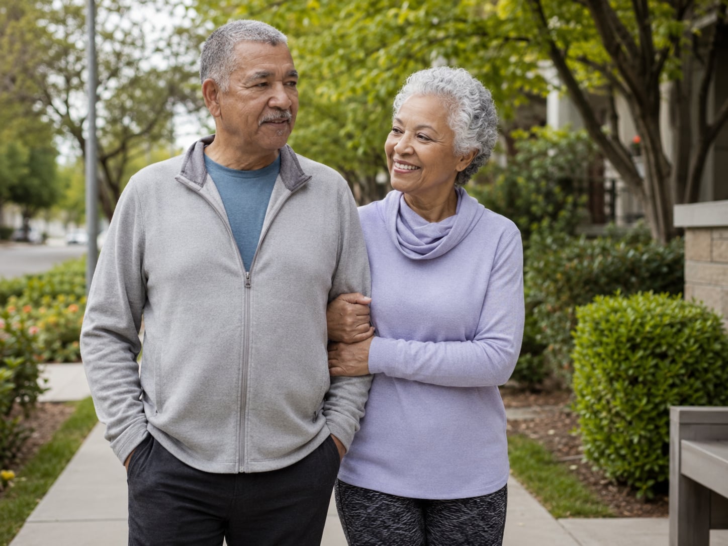 An older man and woman walk arm in arm together outdoors